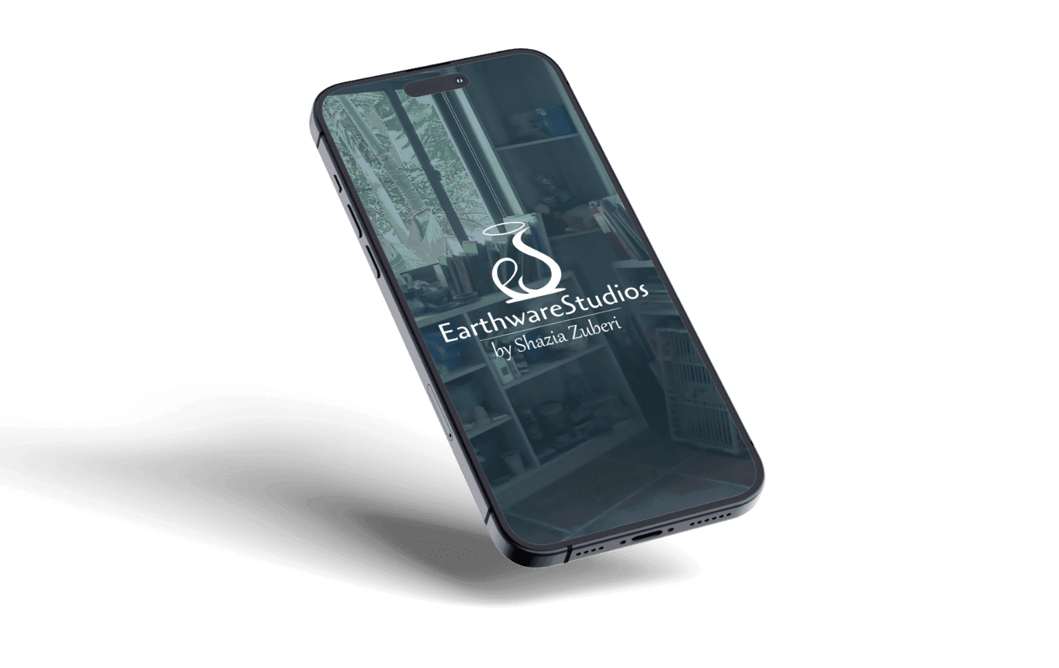 A tilted smartphone displays the "EarthwareStudios by Shazia Zuberi" logo, featuring a stylized pottery design. Reflected studio shelves add a creative ambiance.