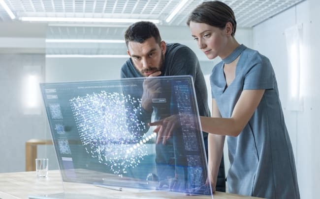 Two professionals examine ethical AI key steps to ensuring fair and responsible AI development with data visualizations in a modern, well-lit workspace.